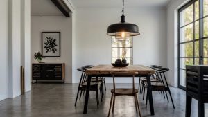 A minimalist dining room with a reclaimed wood table, modern black spindle chairs, and large industrial pendant lighting. 